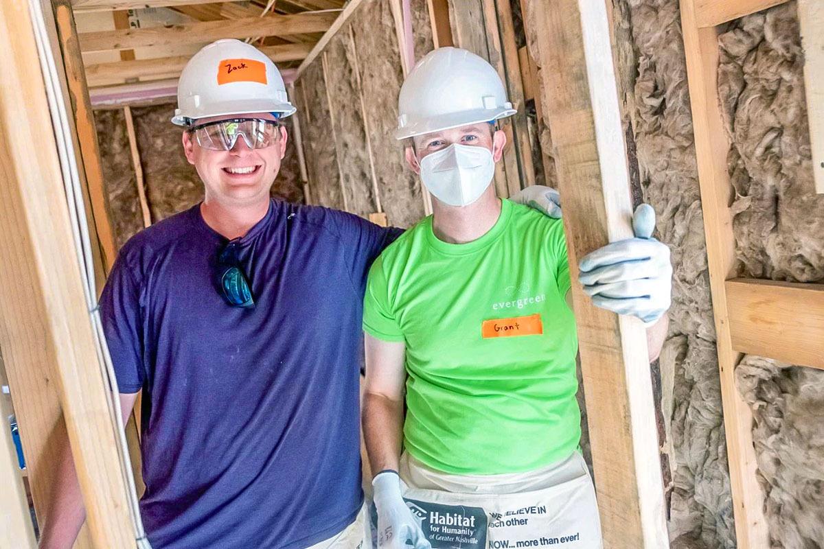 Two people posed in a house under construction.