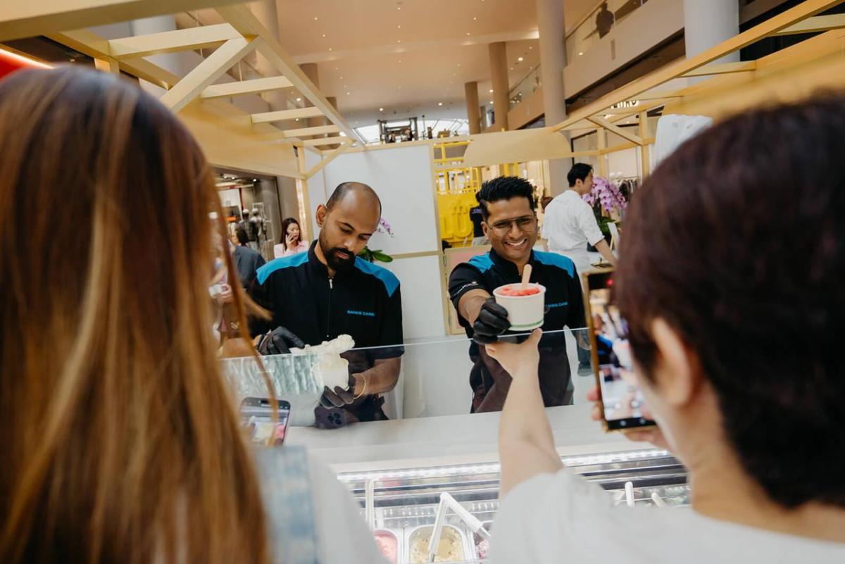 Two volunteers serving ice cream to others.