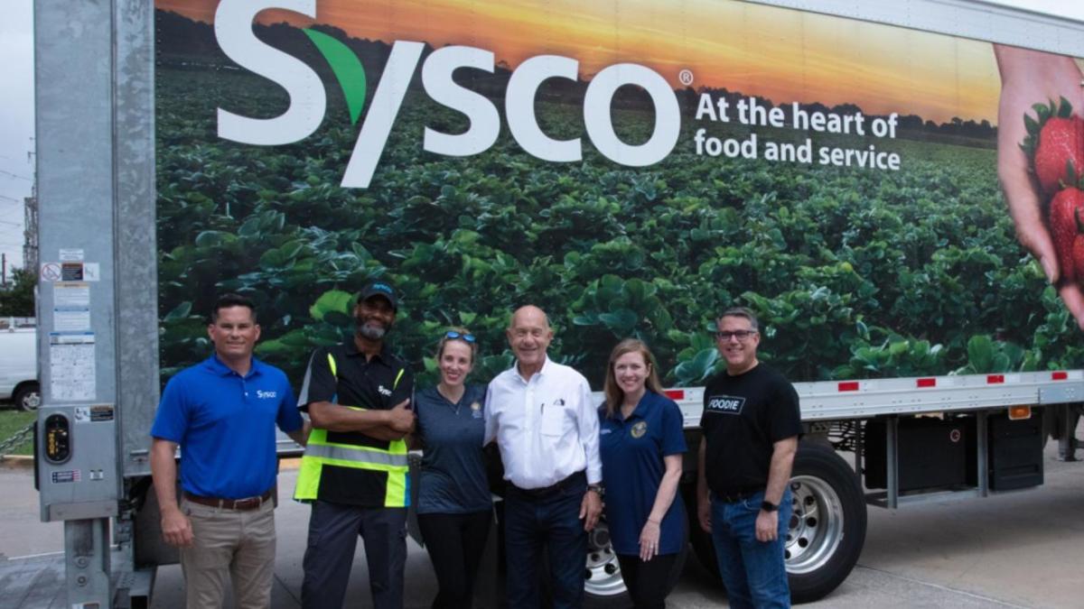 Team of volunteers in front of a truck with Sysco logo on the side.