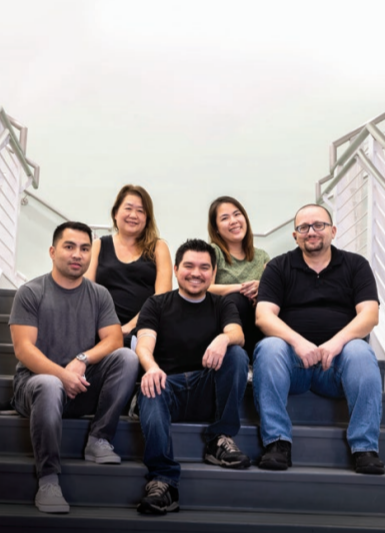 A group of five posed seated on a staircase.