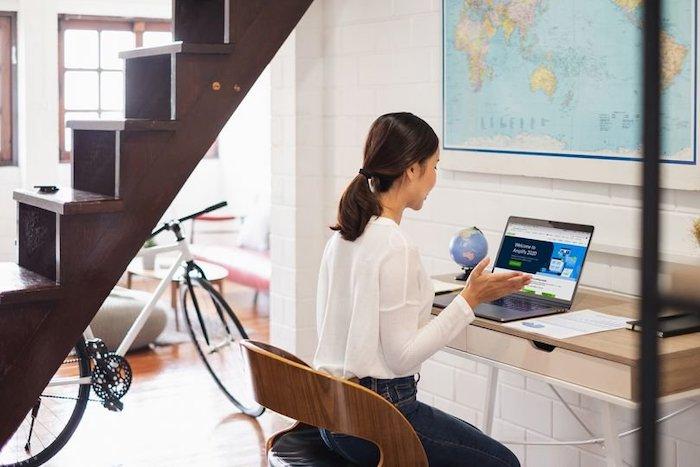 Woman seated at her desk in front of her laptop.