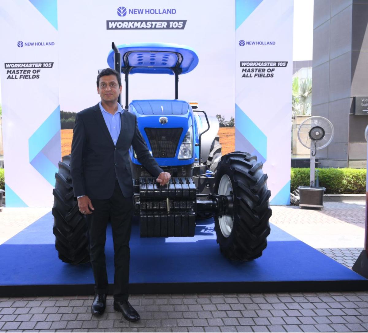 A person standing next to a blue tractor on display.