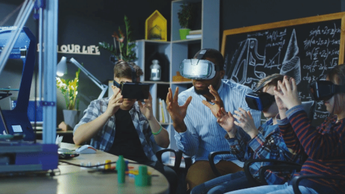 An adult and three children wearing vr headsets and holding hand out in a ball shape in a classroom setting.