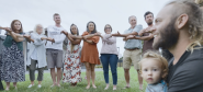 A group of people with interconnected arms standing outside