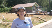 Person speaking in front of house being rebuilt