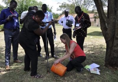 ICRAF soil scientist Leigh Winowiecki demonstrates how to take a topsoil sample with assistance from Leah Mukiite from the Water Resources Authority in Kenya. Photo: World Agroforestry Centre/Hellen Kiarago
