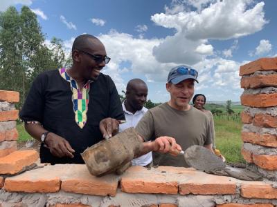 Manasseh Gihana Wandera, Executive Director, Society for Family Health Rwanda (far left), and Fisk Johnson, Chairman and CEO of SC Johnson (center right), help to build a health post in Rwanda – continuing a four-year partnership that provides insights and best practices to help fight malaria around the world.