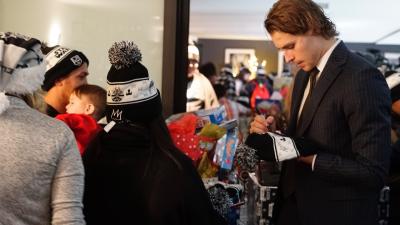 LA Kings forward Adrian Kempe signs a Kings beanie at the LA Kings Adopt-A-Family event at STAPLES Center on December 9, 2017.